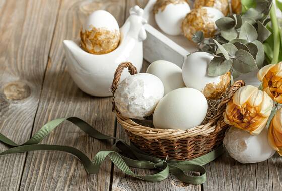 Białe jajka i tulipany na drewnianym blacie. Zdjęcie przykładowe.