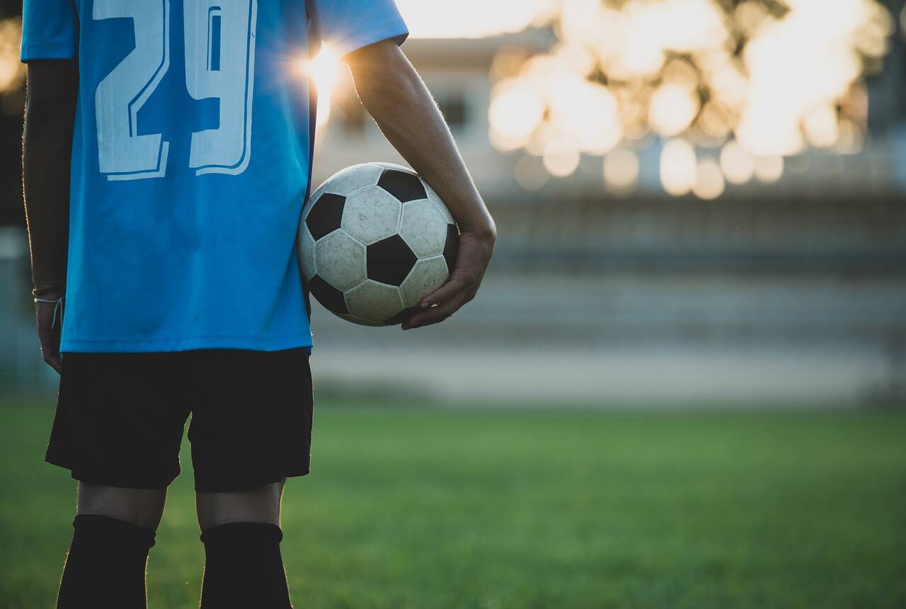 Na przykładowym zdjęciu widać młodego chłopaka trzymającego w rękach piłkę nożną.
