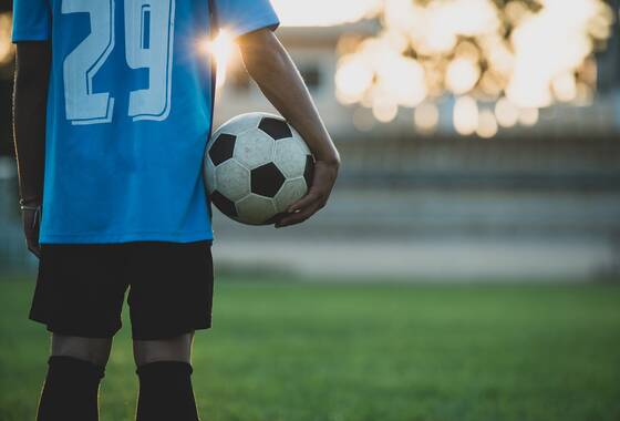Na przykładowym zdjęciu widać młodego chłopaka trzymającego w rękach piłkę nożną.