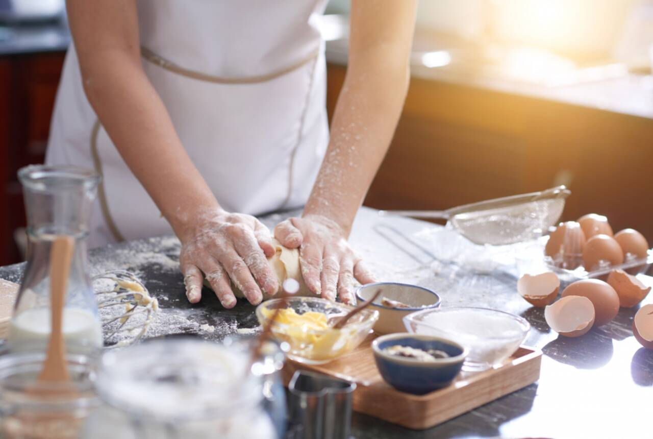 Na fotografii wiać dłonie kobiety, która przygotowuje ciasto na stolnicy