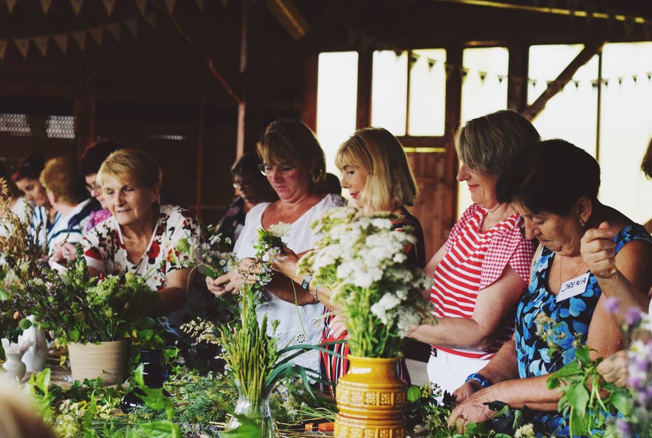 Na fotografii kobiety robiące bukiety z polnych kwiatów 