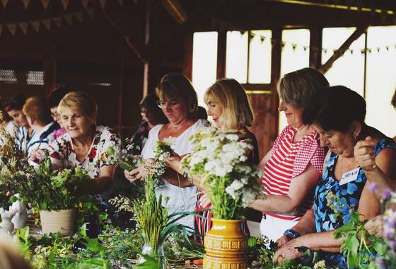 Na fotografii kobiety robiące bukiety z polnych kwiatów 
