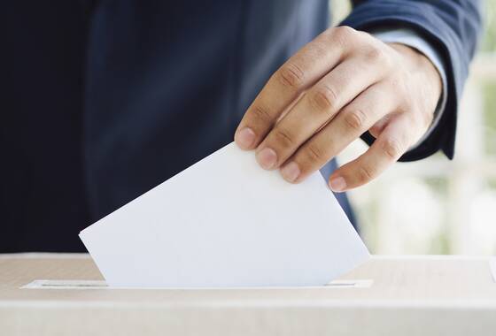 Mężczyzna umieszcza kartę do głosowania w urnie