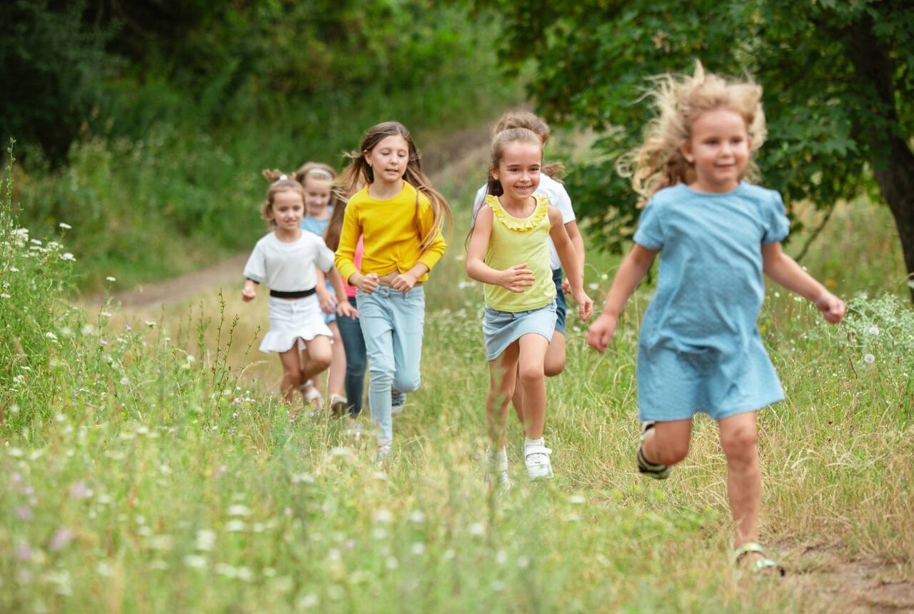 radosne dzieci biegnące przed siebie na tle natury - zdjęcie przykładowe