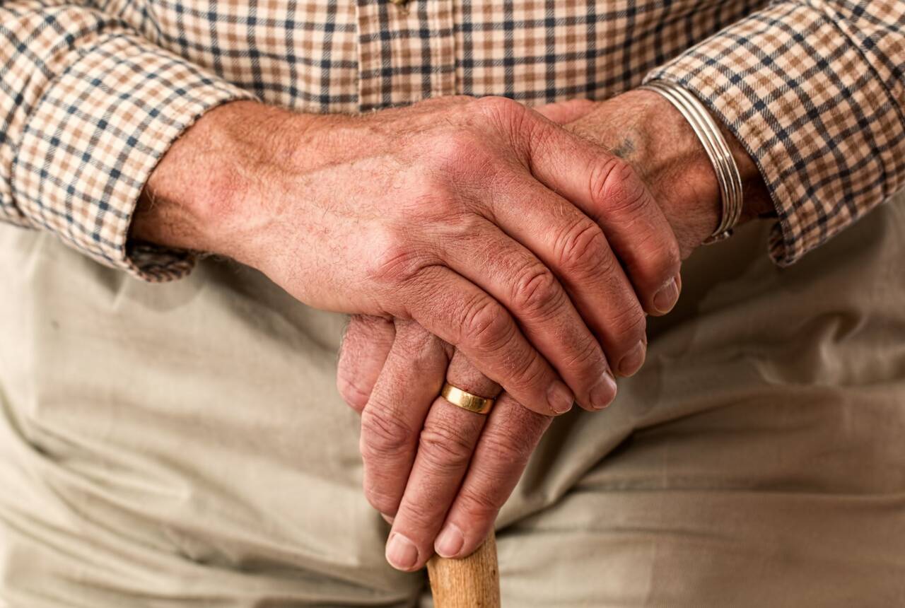 starszy mężczyzna trzymający w dłoniach laskę